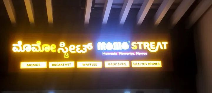 Momo Streat board at night: bilingual lit letters with menu strip